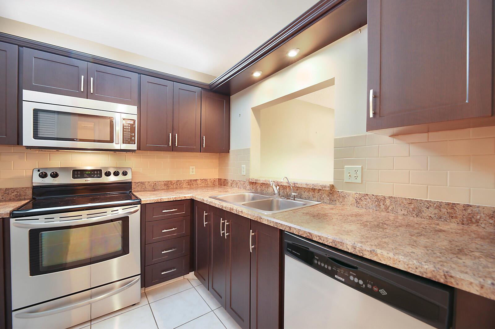 A kitchen with dark wood cabinets, stainless steel appliances, and granite countertops — 3114 SW 20th Terrace, Delray Beach FL 33445, DELRAY BEACH, FL