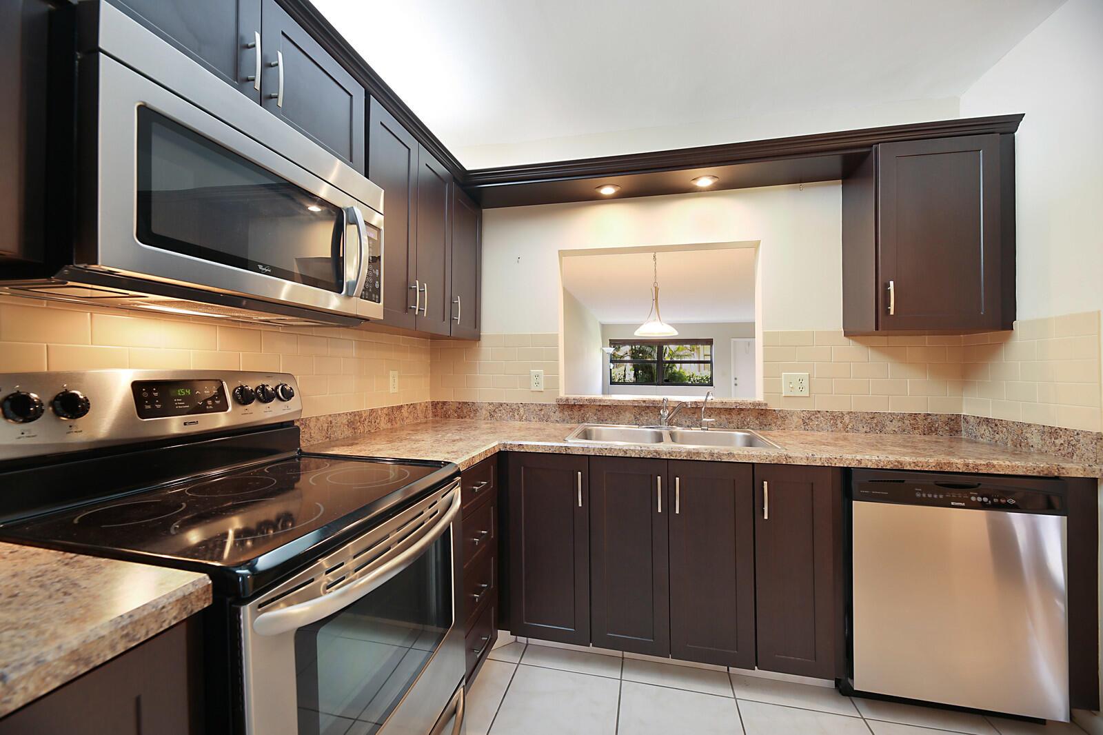 A kitchen with dark wood cabinets, stainless steel appliances, granite countertops, and white tile flooring — 3114 SW 20th Terrace, Delray Beach FL 33445, DELRAY BEACH, FL