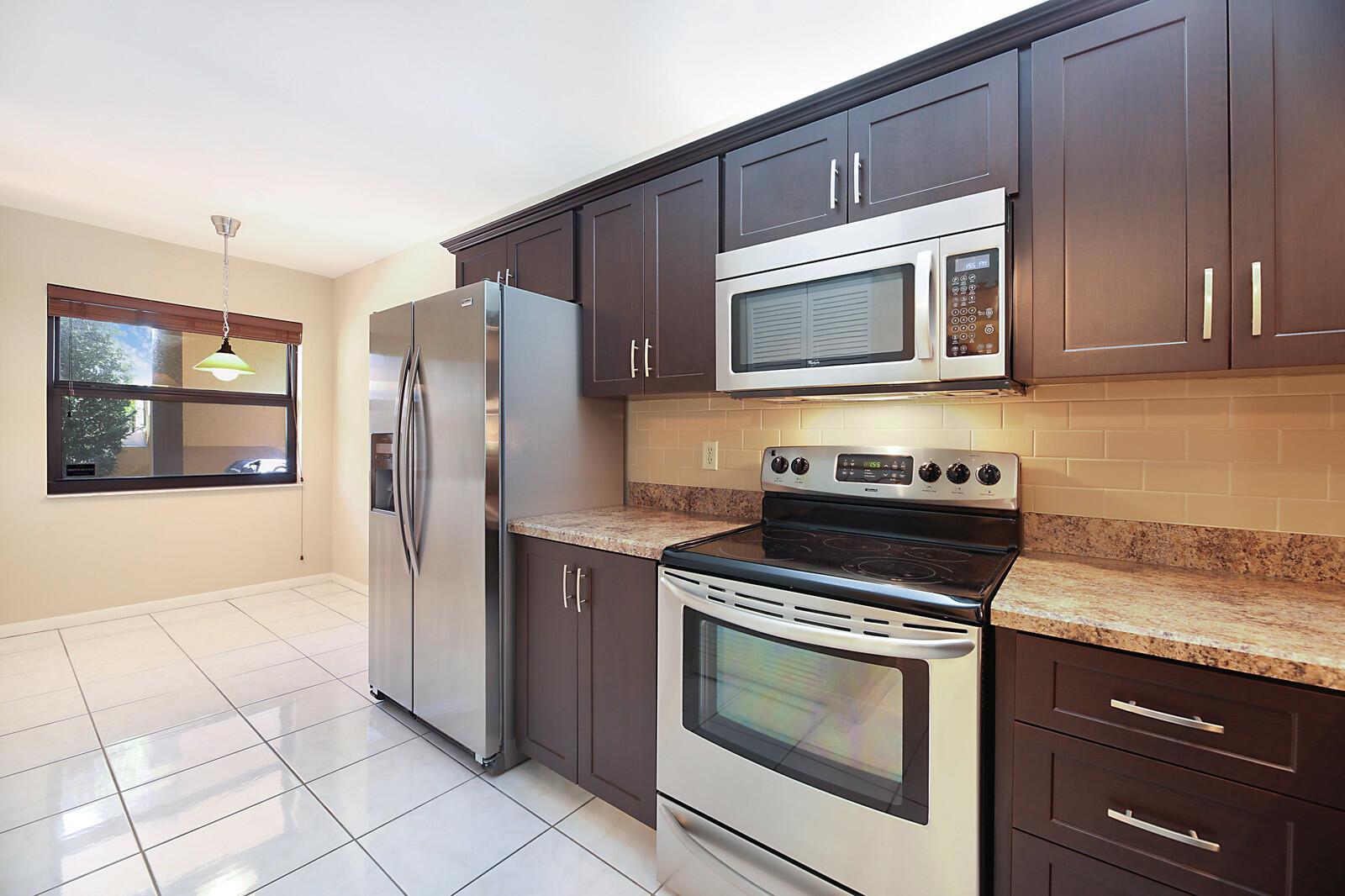 A two-story apartment building with a beige stucco exterior, a balcony, and a fenced patio — 3114 SW 20th Terrace, Delray Beach FL 33445, DELRAY BEACH, FL