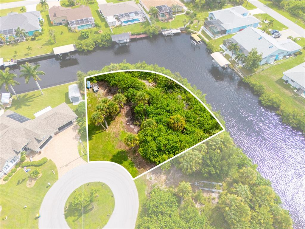 An aerial view shows a vacant, partially wooded waterfront lot located at the end of a cul-de-sac — 4497 BAYVIEW STREET, PORT CHARLOTTE, FL