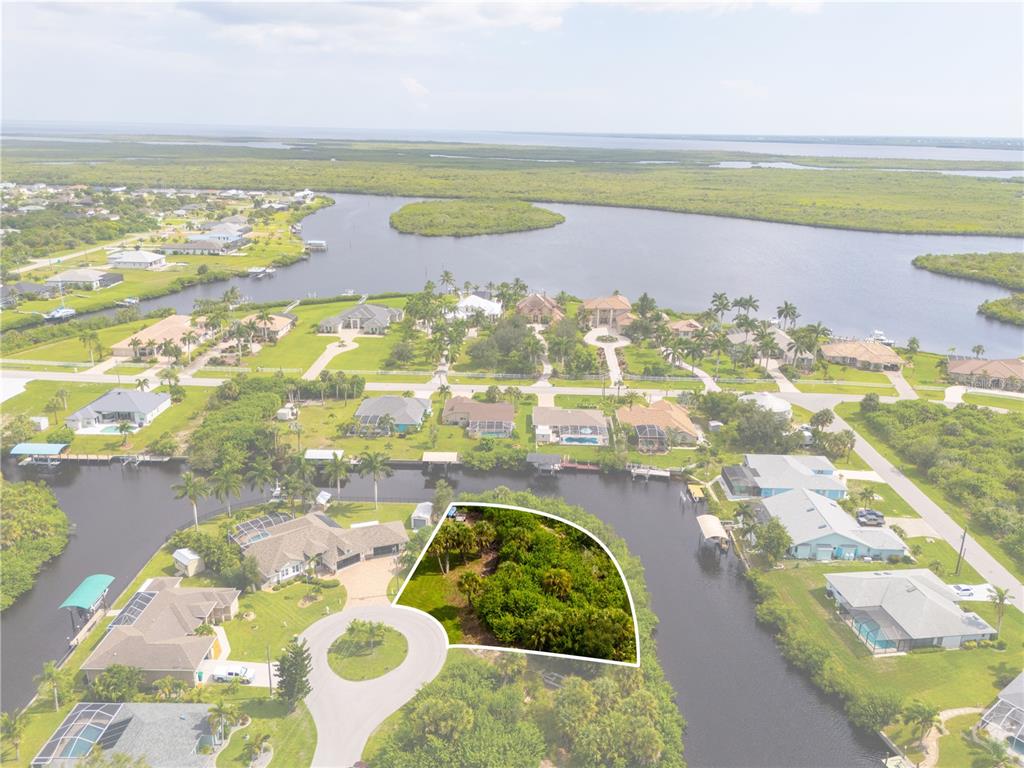 An aerial view shows a vacant, wooded waterfront lot situated at the end of a cul-de-sac — 4497 BAYVIEW STREET, PORT CHARLOTTE, FL