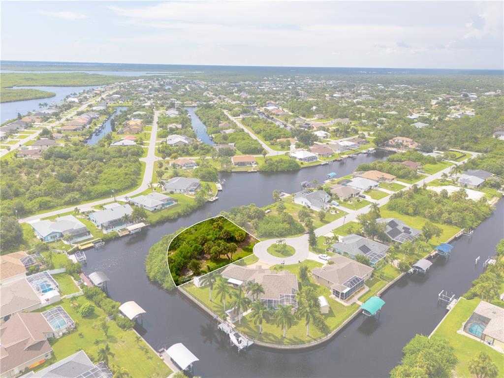 An aerial view shows a vacant, wooded waterfront lot located at the end of a cul-de-sac — 4497 BAYVIEW STREET, PORT CHARLOTTE, FL
