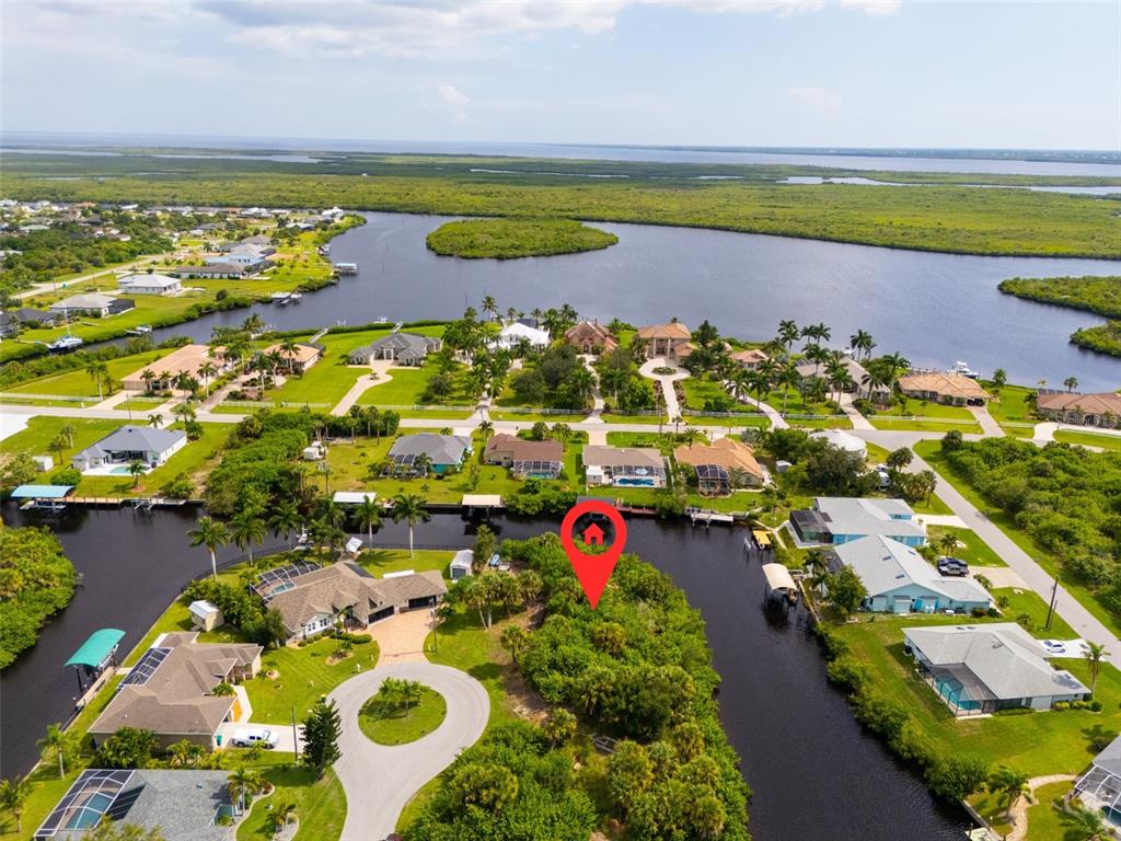 An aerial view shows a vacant, tree-covered waterfront lot marked with a red pin — 4497 BAYVIEW STREET, PORT CHARLOTTE, FL