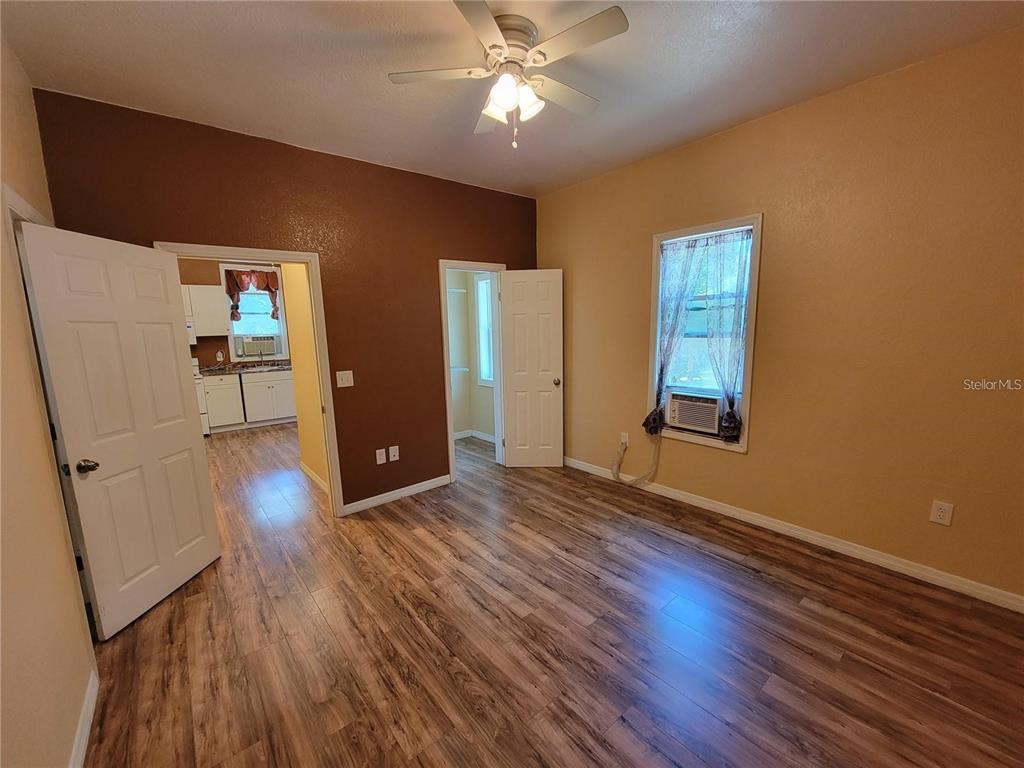 A bedroom with wood-look flooring, a ceiling fan, and two doorways leading to other rooms — 965 NE 2ND STREET UNIT 4, OCALA, FL