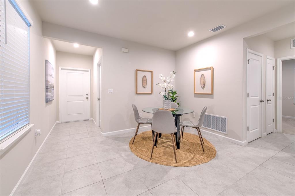 A dining area features a glass-topped table, three chairs, a round rug, and tile flooring — 11836 BRISTOL BRIDGE ROAD, SPRING HILL, FL