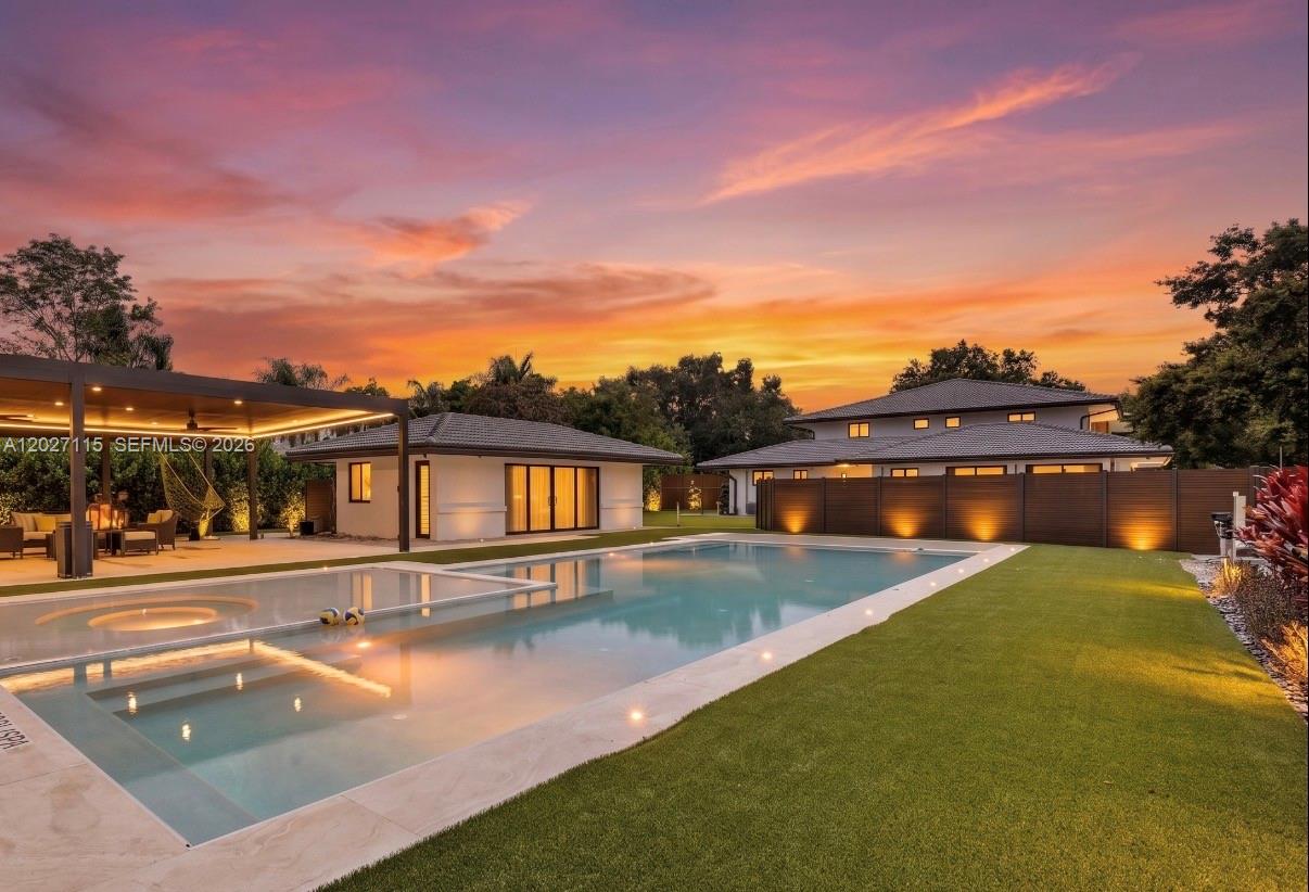 A swimming pool with a covered patio and a modern house at sunset — 12111 NW 5th Ct, Plantation FL 33325, PLANTATION, FL