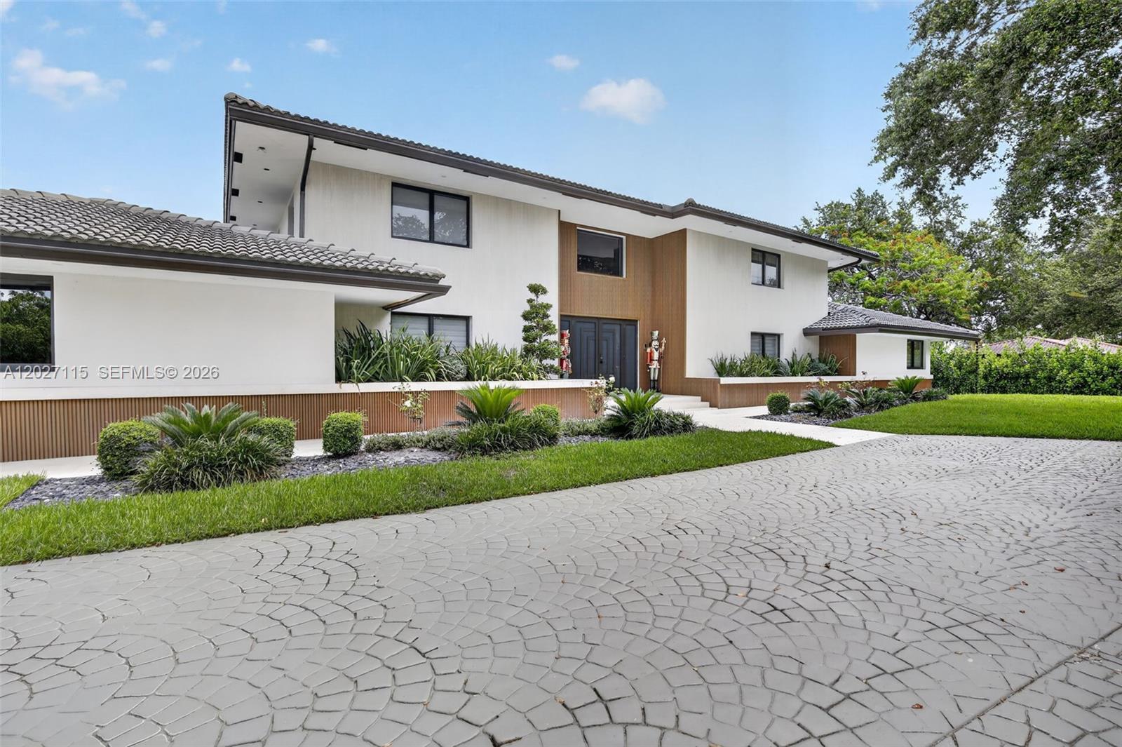 A two-story house with a patterned concrete driveway, white stucco walls, and wood-paneled accents — 12111 NW 5th Ct, Plantation FL 33325, PLANTATION, FL