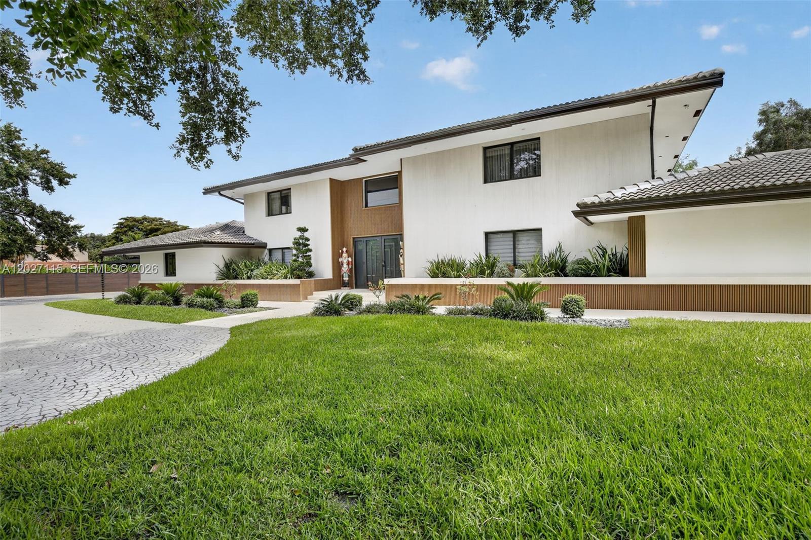 A two-story house with white stucco walls, wood-paneled accents, and a tiled roof — 12111 NW 5th Ct, Plantation FL 33325, PLANTATION, FL