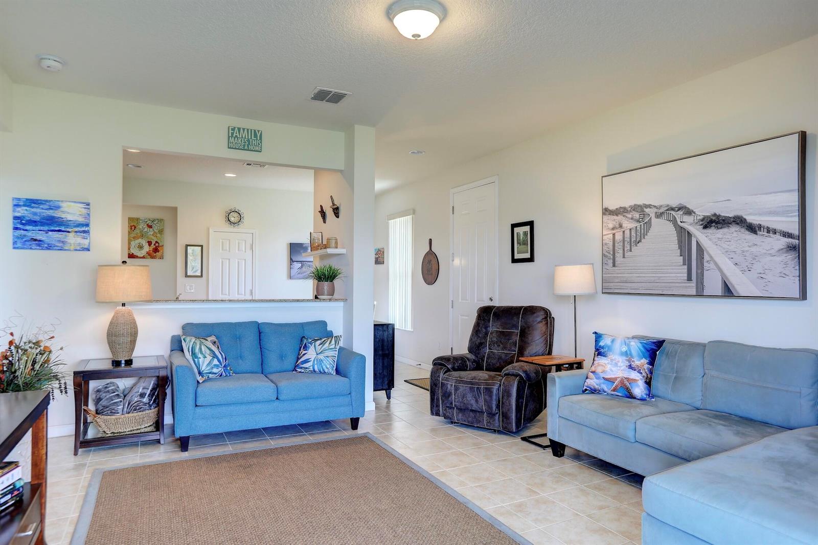 A living room features two blue sofas, a brown recliner, and tiled flooring — 1420 Dittmer Circle SE, Palm Bay FL 32909, PALM BAY, FL