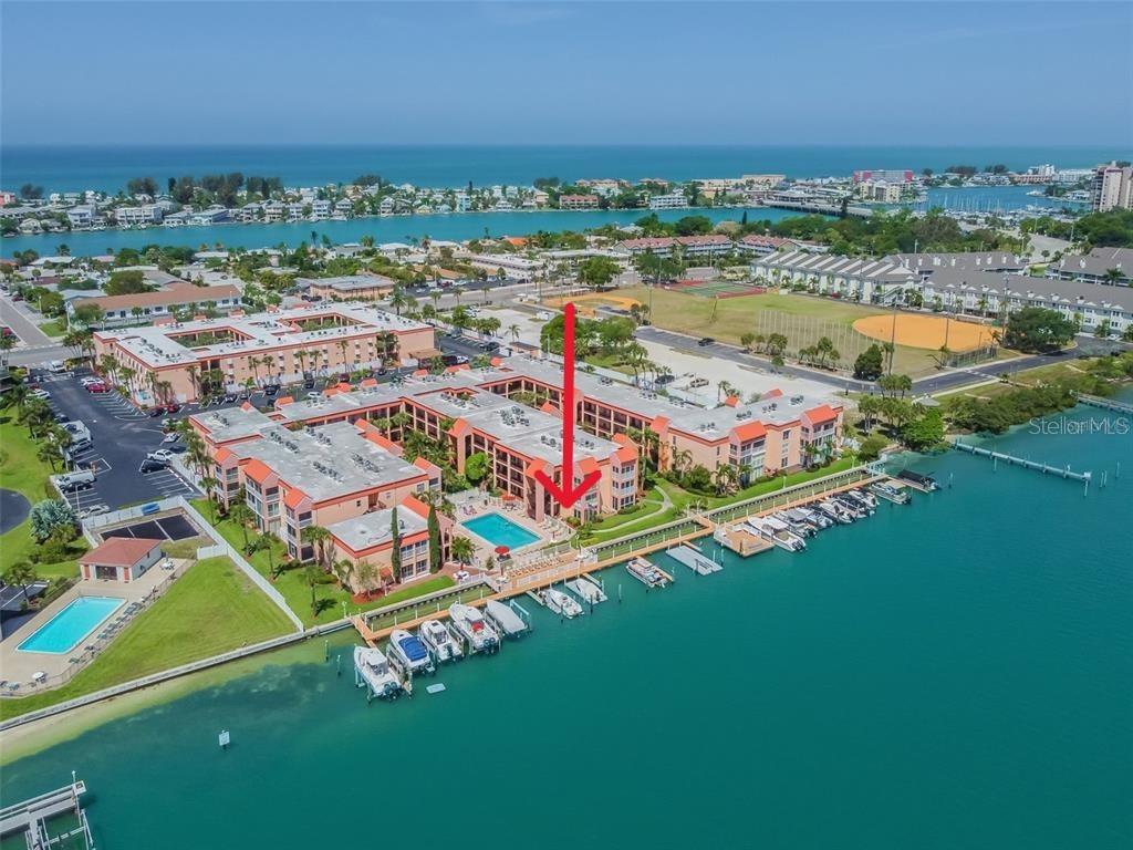 An aerial view of a waterfront apartment complex with a swimming pool and boat slips — 8921 BLIND PASS ROAD UNIT 143, ST PETE BEACH, FL