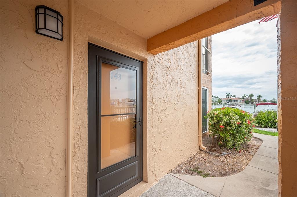A view of a building exterior entrance with a dark door and a waterfront view — 8921 BLIND PASS ROAD UNIT 143, ST PETE BEACH, FL