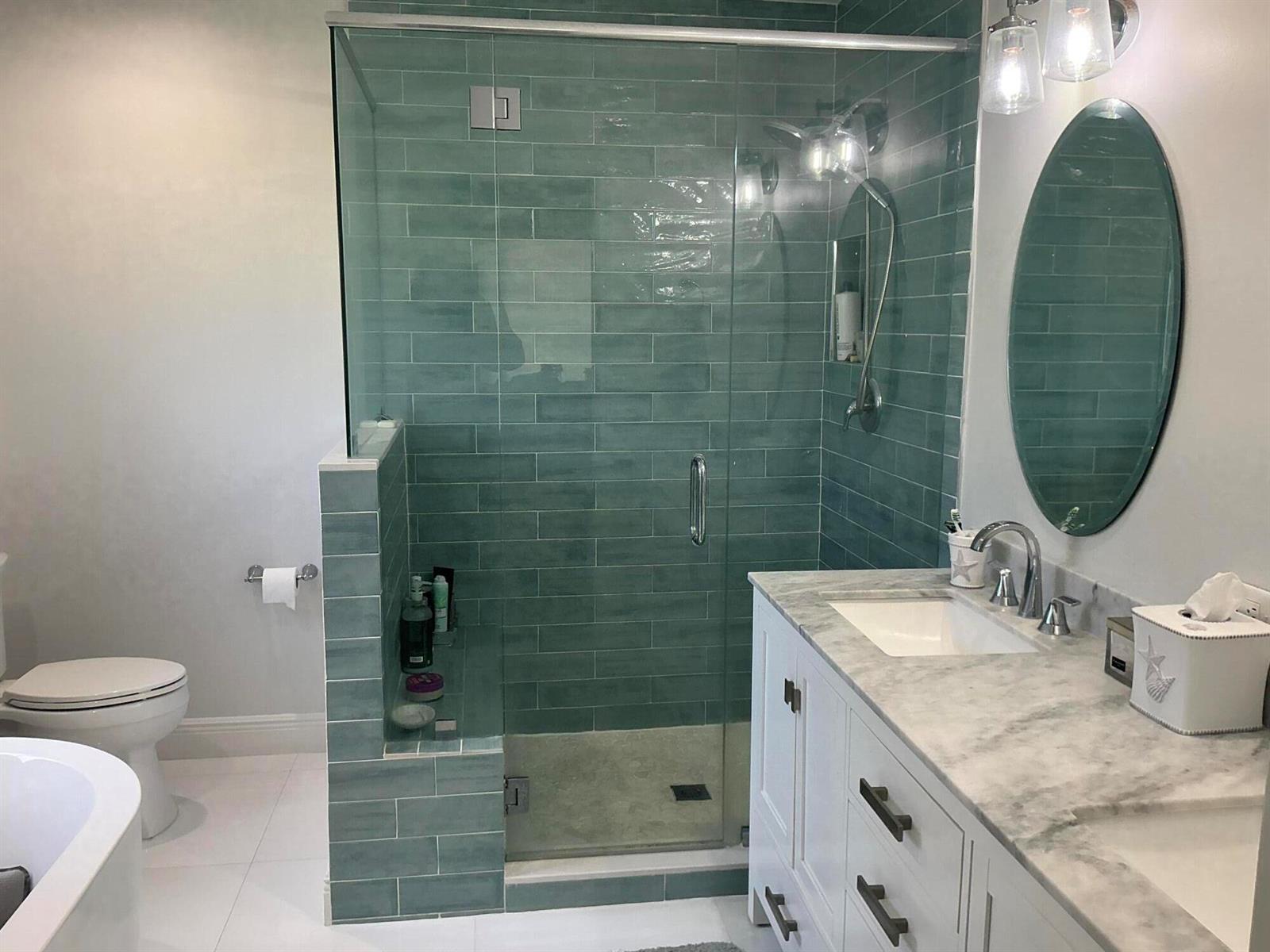 A bathroom features a glass-enclosed shower with teal subway tiles, a white vanity, and toilet — 18 Holly Drive, Boynton Beach FL 33436, BOYNTON BEACH, FL