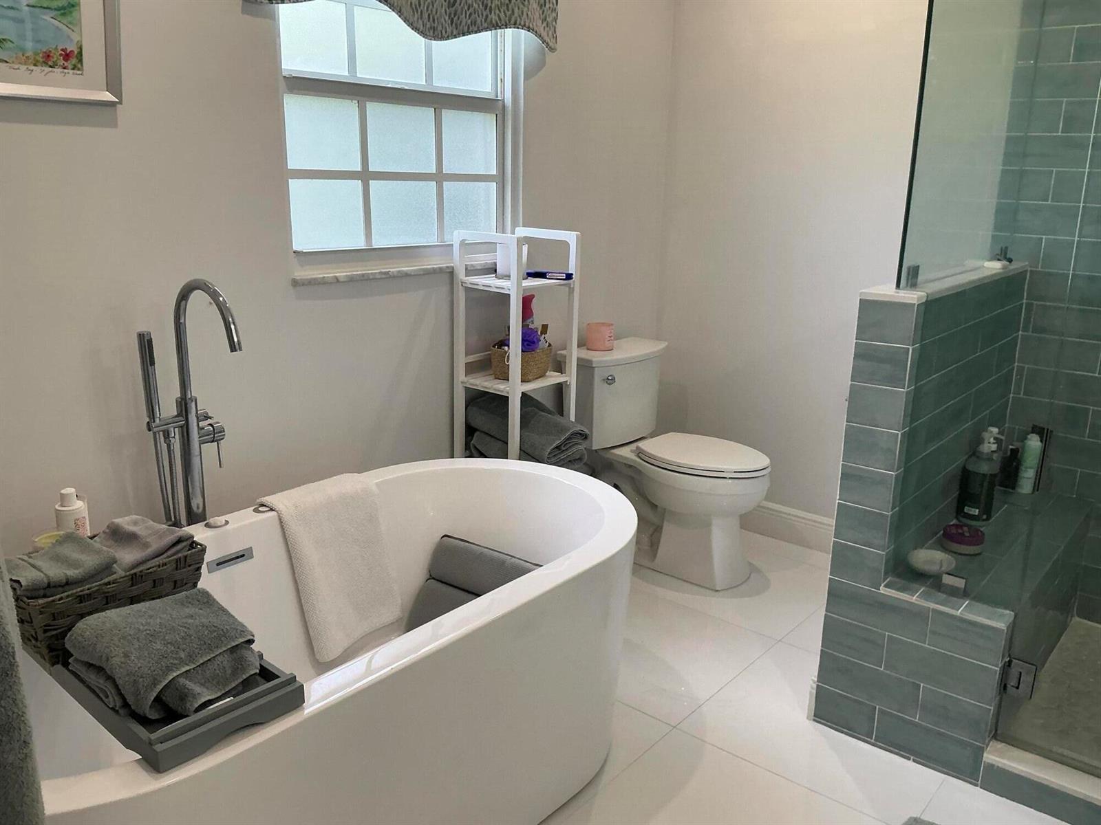A bathroom features a freestanding tub, a toilet, and a glass-enclosed shower with blue tiles — 18 Holly Drive, Boynton Beach FL 33436, BOYNTON BEACH, FL