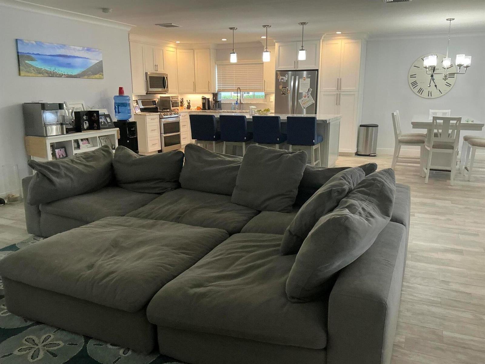 A large gray sectional sofa faces an open-concept kitchen with white cabinets and a breakfast bar — 18 Holly Drive, Boynton Beach FL 33436, BOYNTON BEACH, FL