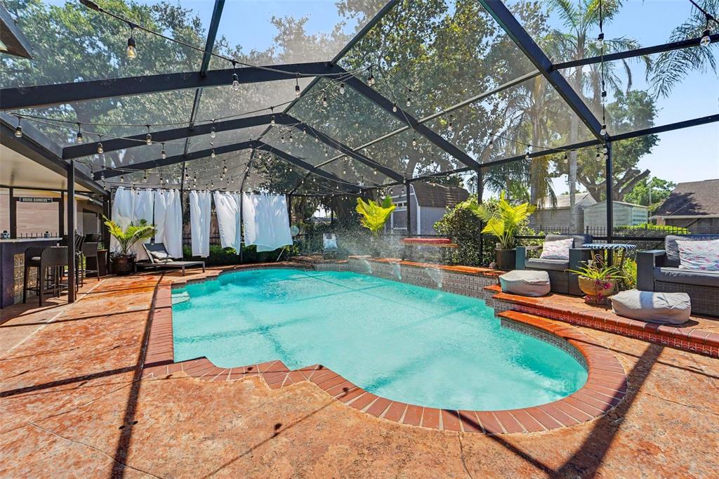 A screened-in swimming pool with a brick-trimmed deck, water features, and outdoor seating — 717 CAMROSE DRIVE, BRANDON, FL