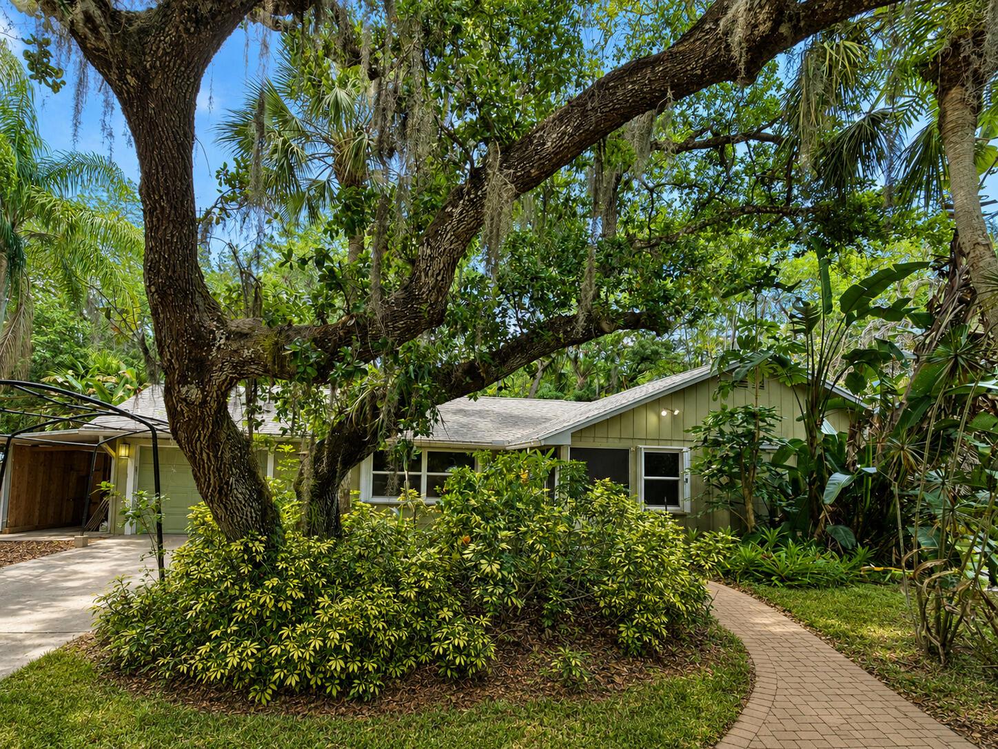 A green house with a large oak tree and a brick walkway in the front yard — 255 SW Salerno Road, Stuart FL 34997, STUART, FL