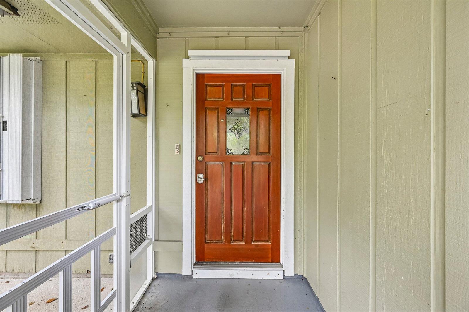 A wooden front door with a decorative glass panel sits on a covered porch — 255 SW Salerno Road, Stuart FL 34997, STUART, FL