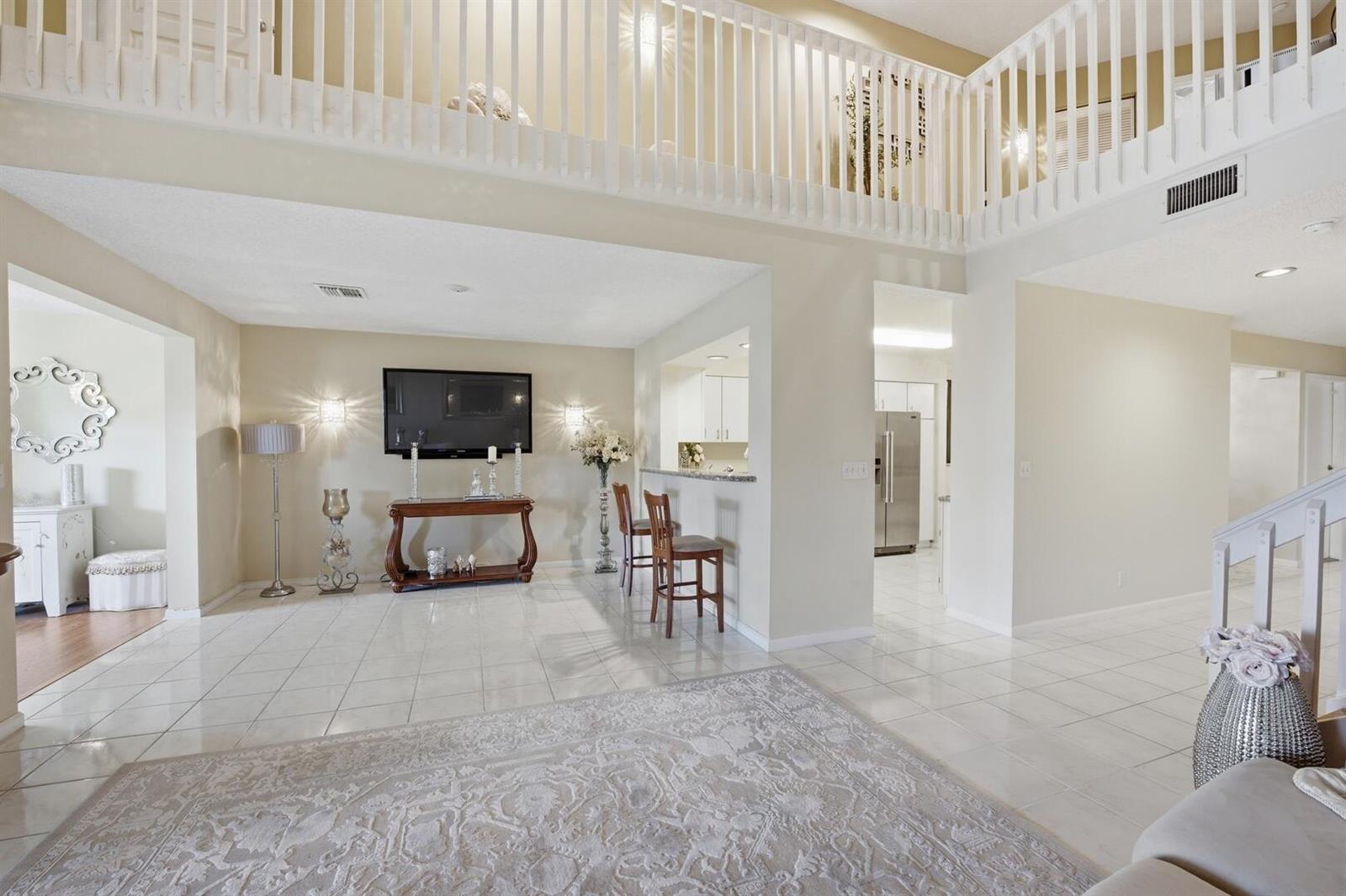 A spacious living area features white tile floors, a lofted balcony, and an open kitchen — 9172 Boca Gardens Parkway # B, Boca Raton FL 33496, BOCA RATON, FL