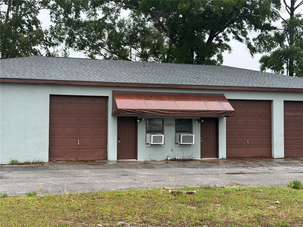 A single-story commercial building features two garage doors, two entry doors, and window air conditioners — 10858 SW 91ST AVENUE, OCALA, FL