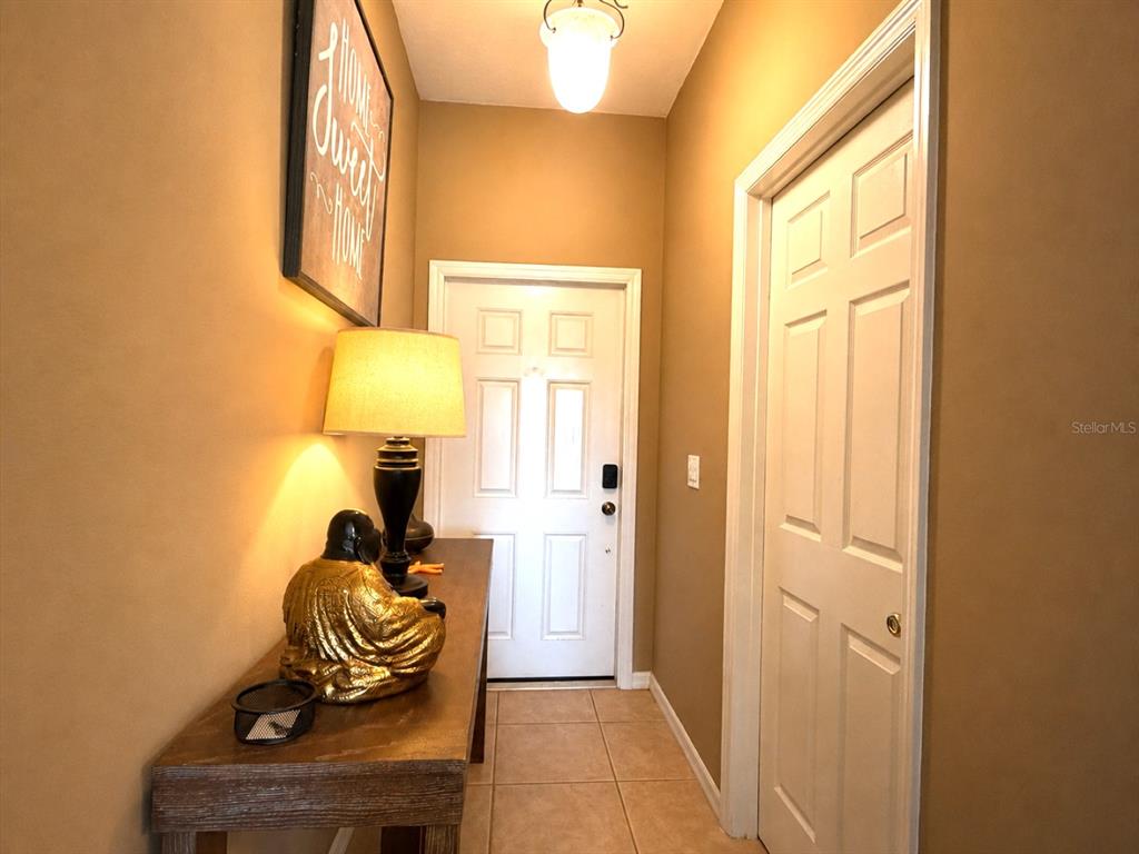 An entryway features a console table with a lamp and statue, tile flooring, and doors — 1720 RETREAT VIEW CIRCLE, SANFORD, FL