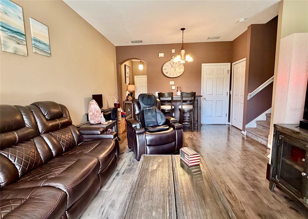 A living room with wood-look flooring, a brown leather sofa, and an adjacent dining area — 1720 RETREAT VIEW CIRCLE, SANFORD, FL