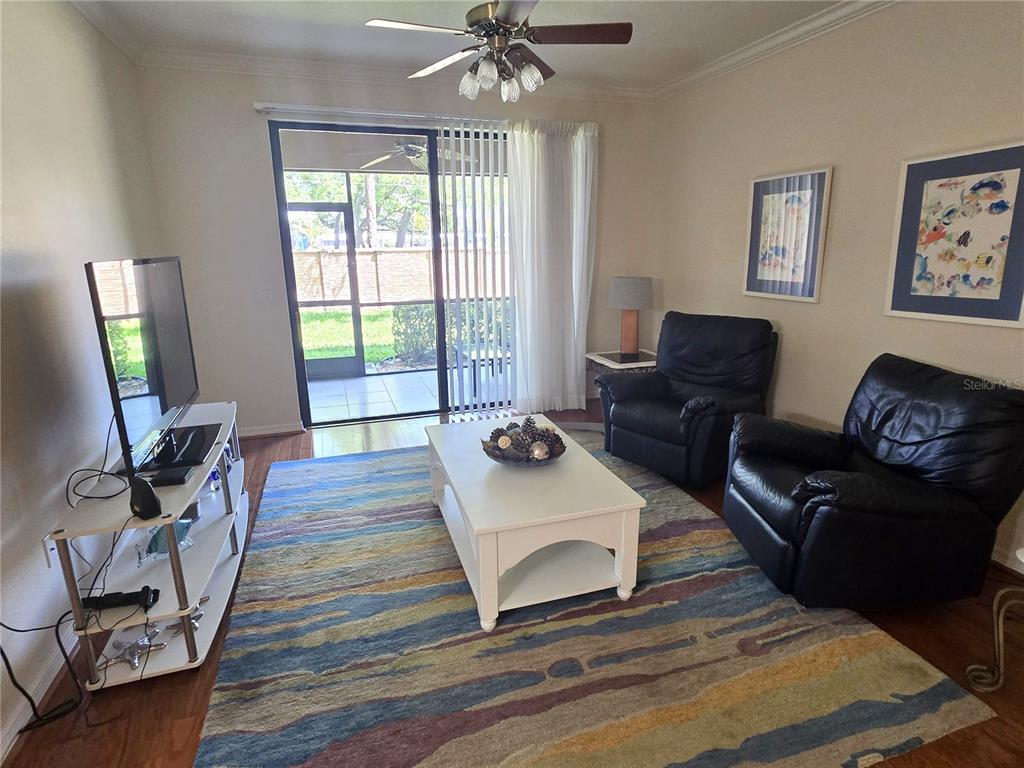 A living room features two black leather recliners, a white coffee table, and sliding glass doors — 4005 OVERTURE CIRCLE UNIT 4005, BRADENTON, FL