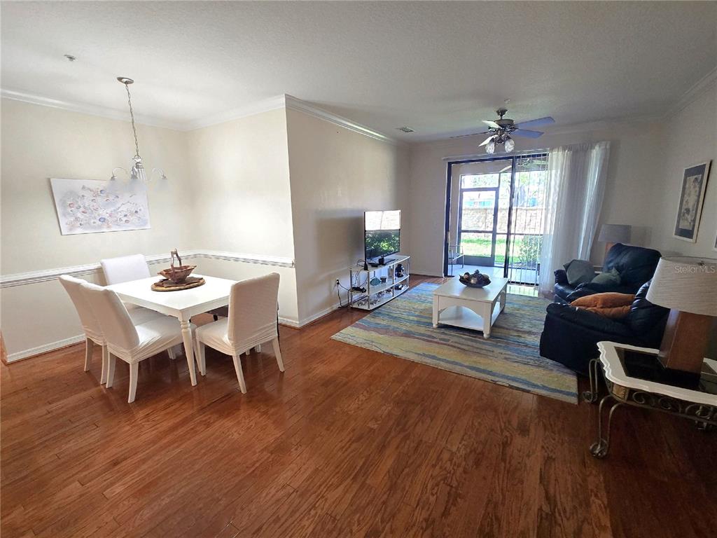 An open-concept living and dining area features hardwood floors, a ceiling fan, and sliding glass doors — 4005 OVERTURE CIRCLE UNIT 4005, BRADENTON, FL