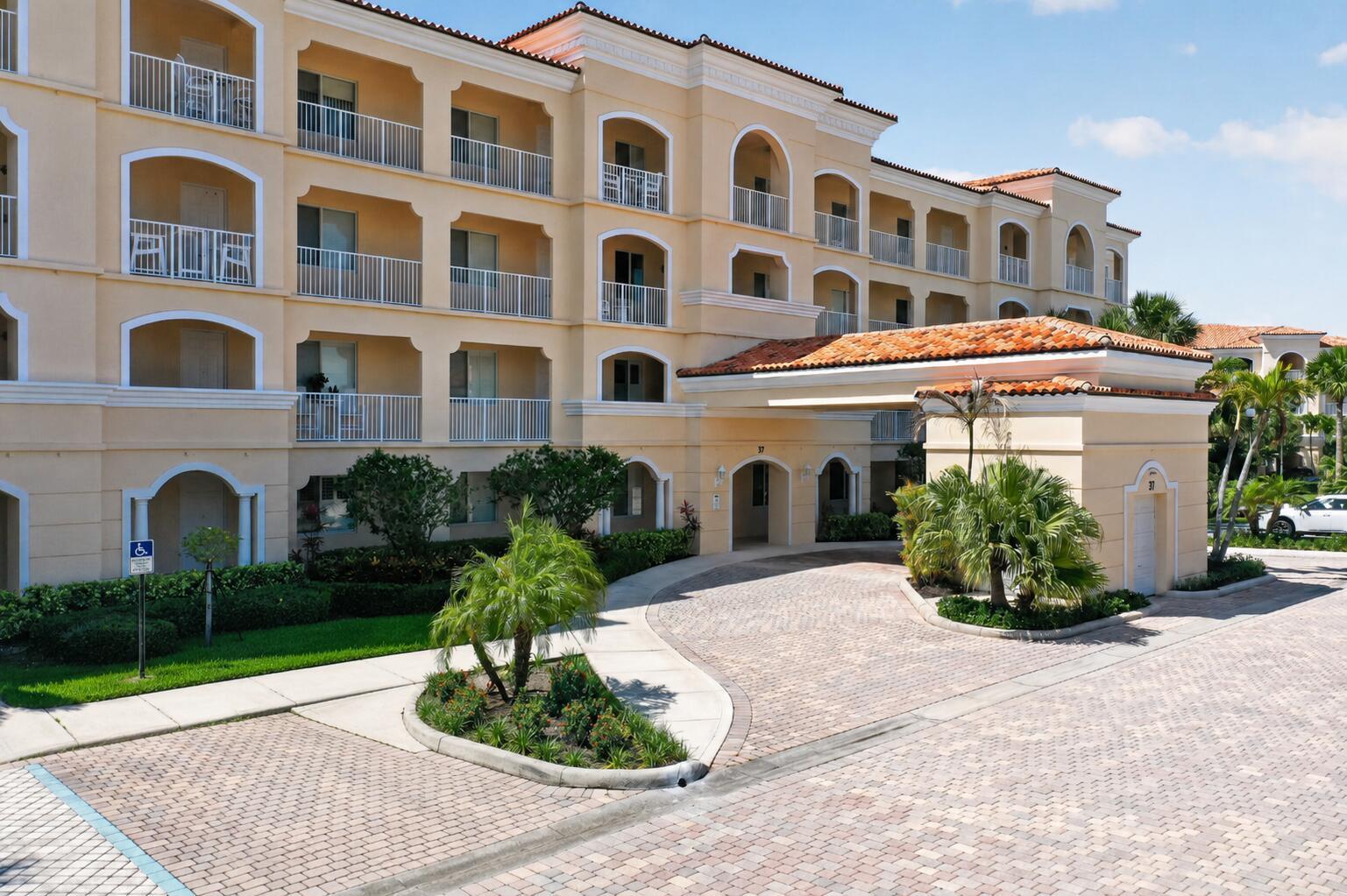 A multi-story beige stucco building with arched balconies and a tiled porte-cochère entrance — 37 E Harbour Isle Dr Drive E # 106, Fort Pierce FL 34949, FORT PIERCE, FL