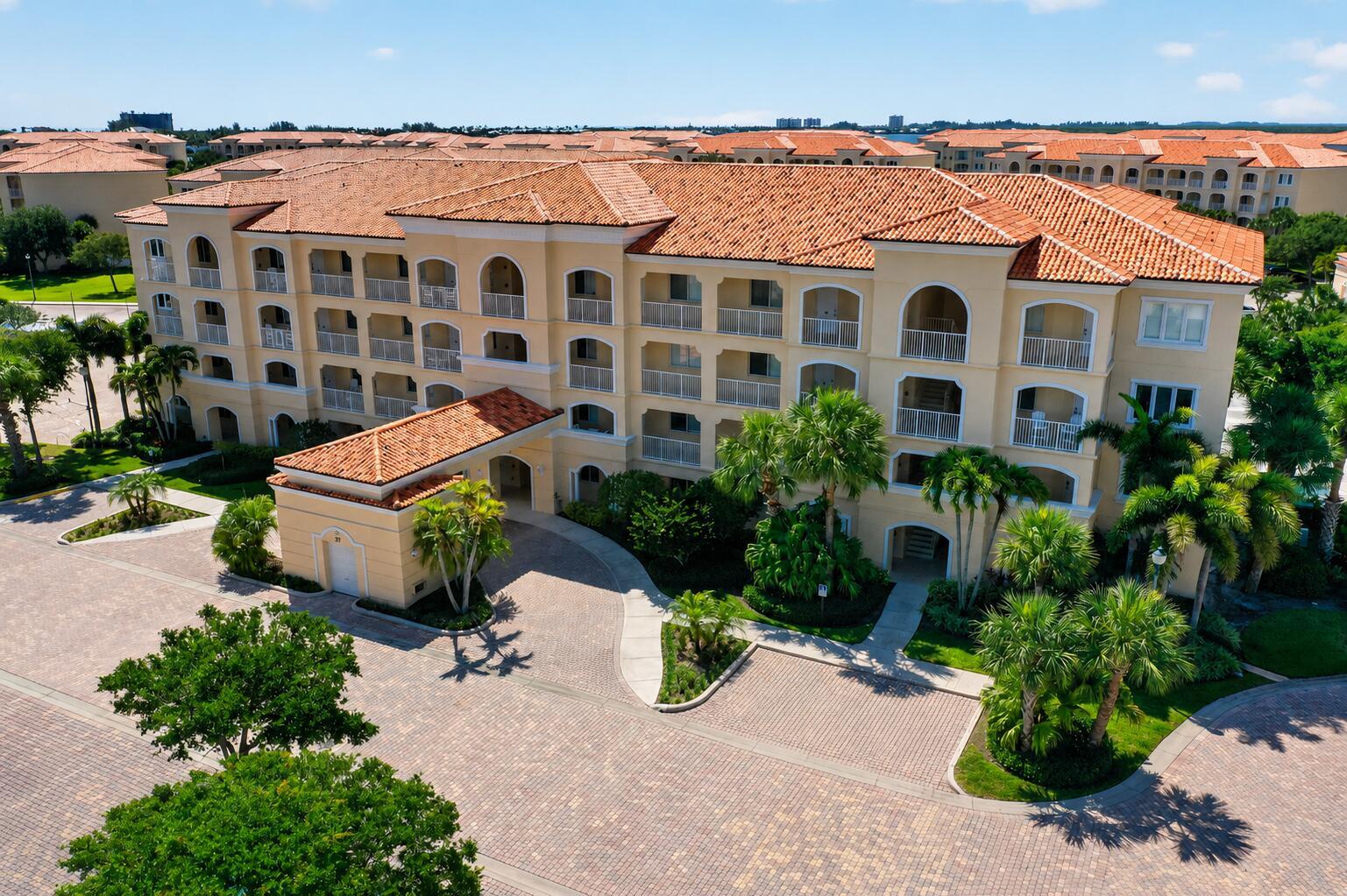 An aerial view of a multi-story Mediterranean-style apartment building with a tiled roof and driveway — 37 E Harbour Isle Dr Drive E # 106, Fort Pierce FL 34949, FORT PIERCE, FL