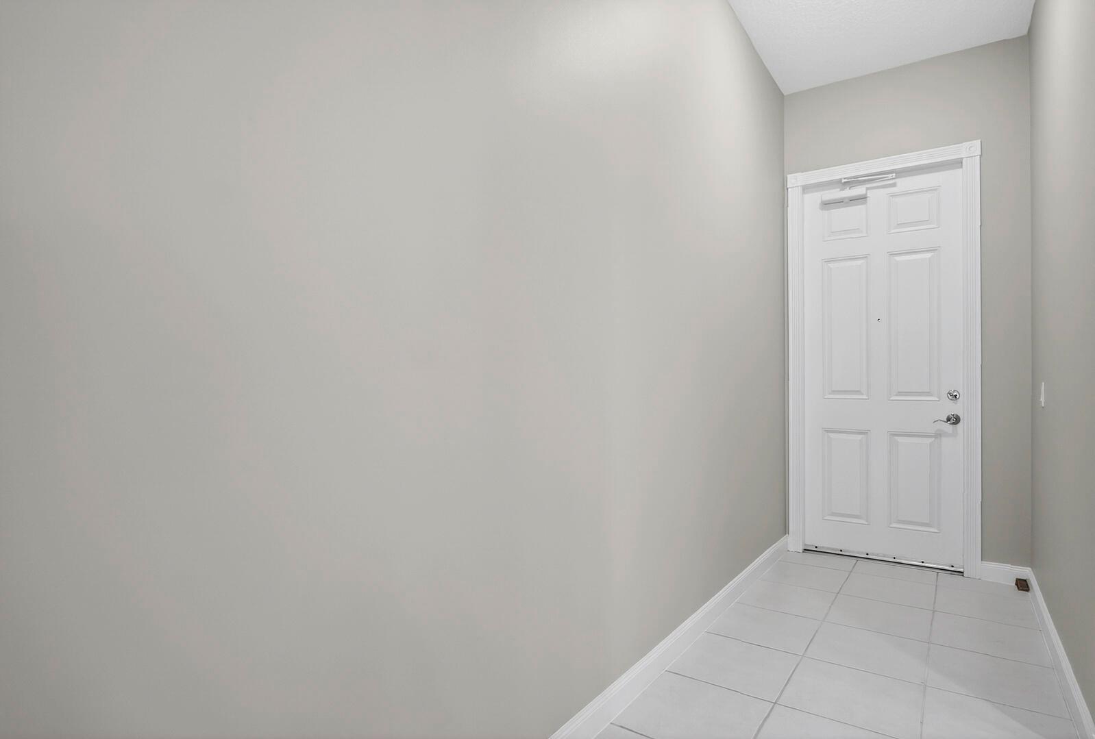 A white door with a silver closer opens into a small foyer with tiled flooring — 37 E Harbour Isle Dr Drive E # 106, Fort Pierce FL 34949, FORT PIERCE, FL