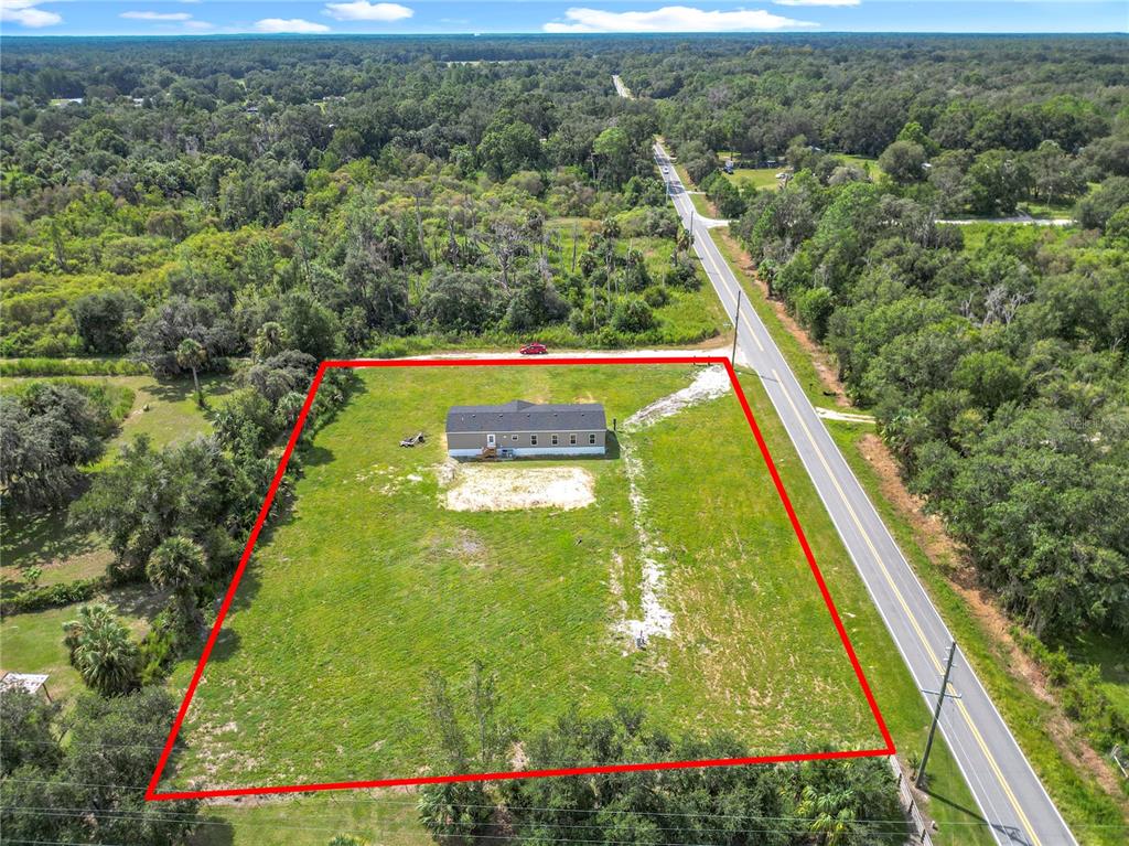 An aerial view shows a single-story house situated on a large, grassy, rectangular lot — 8969 W CANDLEGLOW STREET, CRYSTAL RIVER, FL
