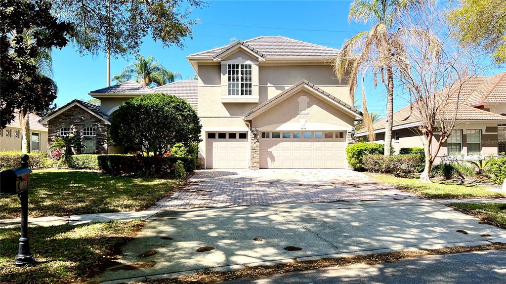 A two-story suburban house features a paved driveway, a three-car garage, and a tiled roof — 8854 OAK LANDINGS COURT, ORLANDO, FL