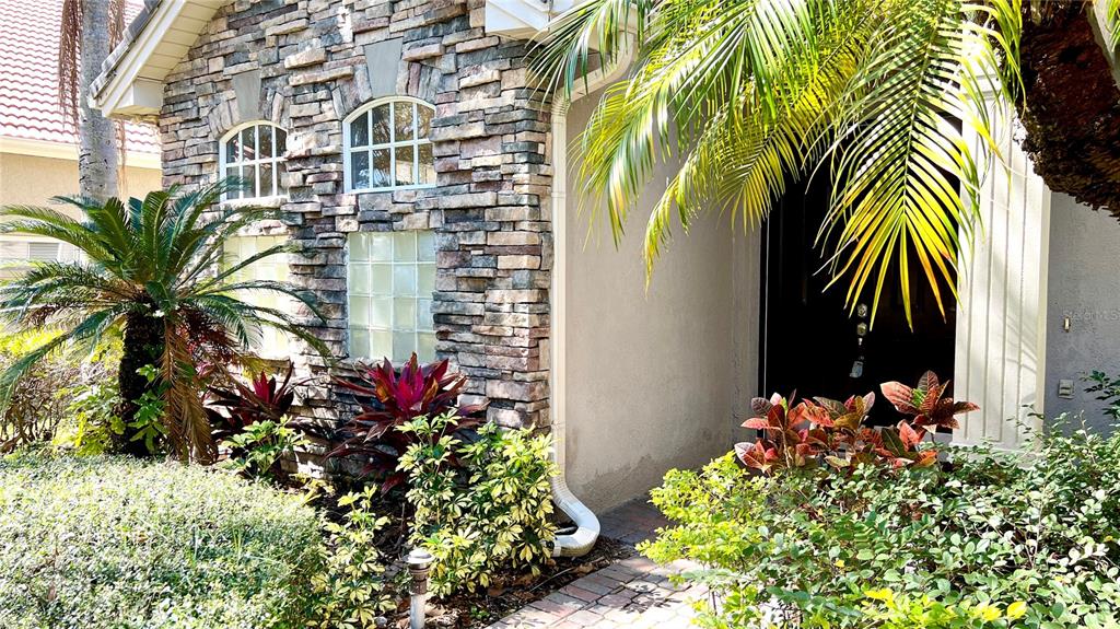 The exterior of a home features stone veneer siding, arched windows, and a landscaped entryway — 8854 OAK LANDINGS COURT, ORLANDO, FL