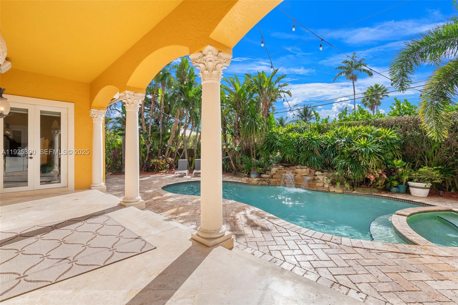 A covered patio with columns overlooks a swimming pool with a stone waterfall feature — 3406 Leigh Rd, Pompano Beach FL 33062, POMPANO BEACH, FL
