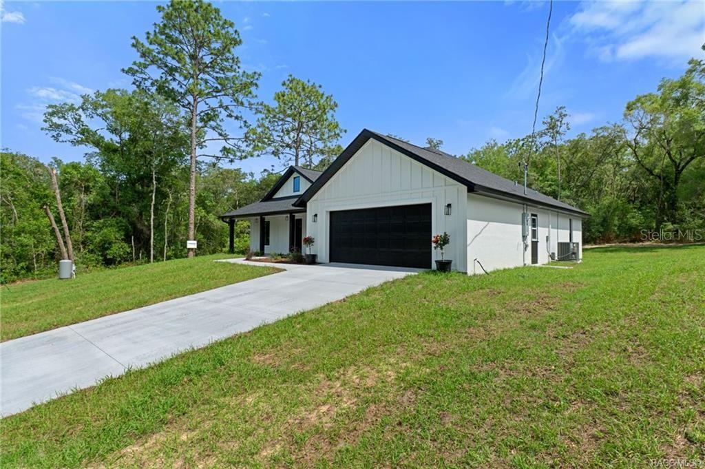 A white house with black trim and a garage sits on a grassy lot — 3058 E CROWN DRIVE, INVERNESS, FL