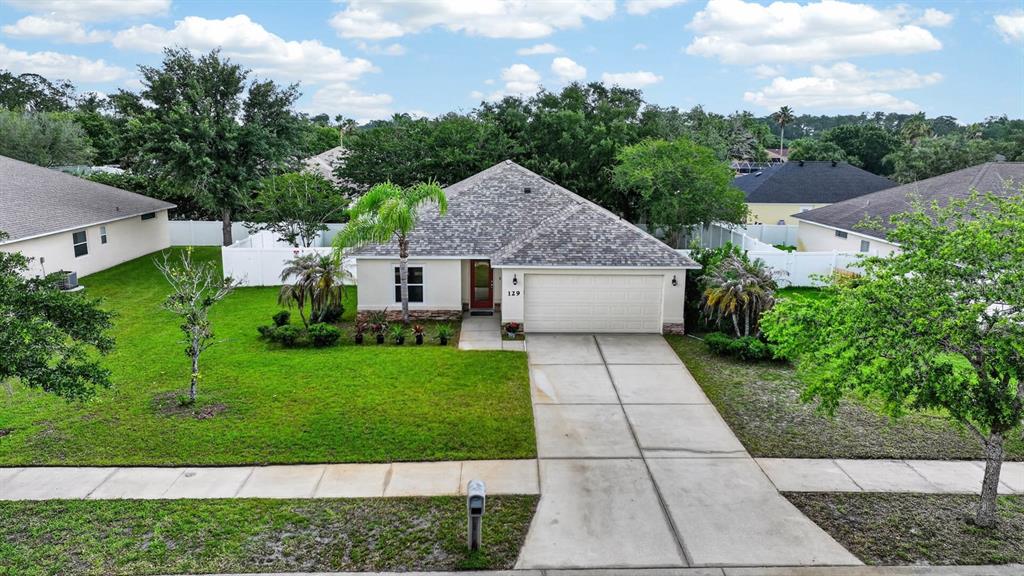 An exterior view of a single-story suburban house with a driveway and front lawn — 129 GREY DAPPLE WAY, ORMOND BEACH, FL