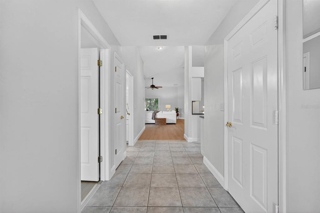 A tiled hallway leads to a living area with white walls and light wood flooring — 129 GREY DAPPLE WAY, ORMOND BEACH, FL