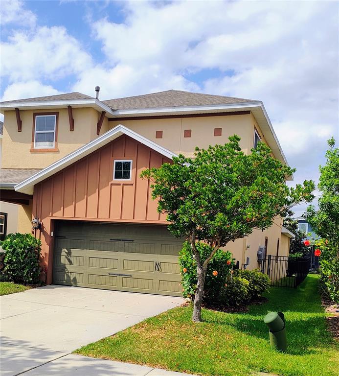 A two-story house features a tan stucco exterior, a brown garage door, and a tree — 7508 SEA LILLY COURT, APOLLO BEACH, FL