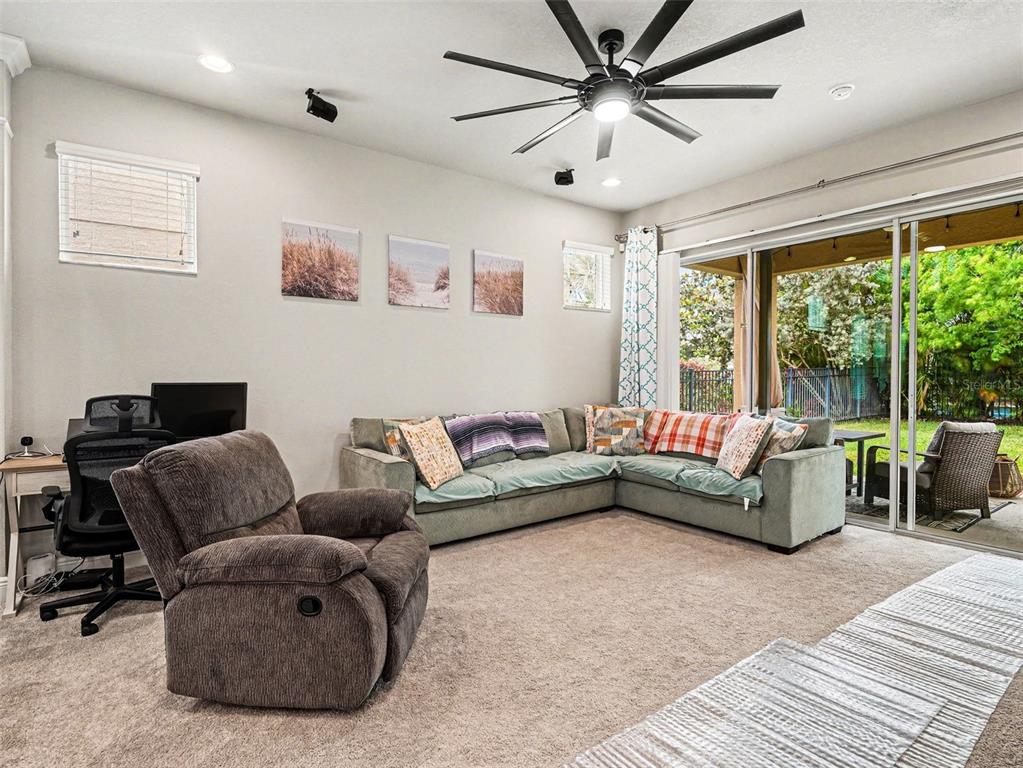 A living room features a sectional sofa, a recliner, a desk, and sliding glass doors — 7508 SEA LILLY COURT, APOLLO BEACH, FL
