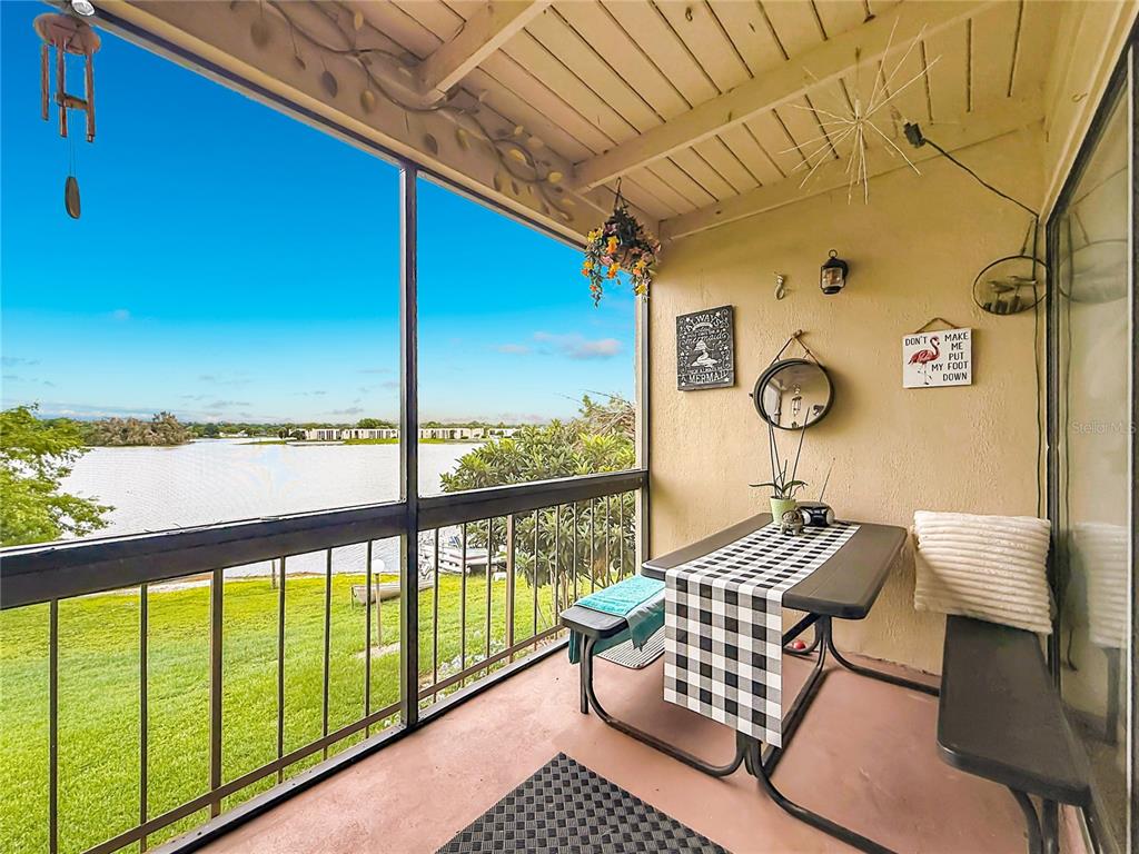 A screened-in porch features a dining table, wall decor, and a view of a lake — 574 ORANGE DRIVE UNIT 78, ALTAMONTE SPRINGS, FL