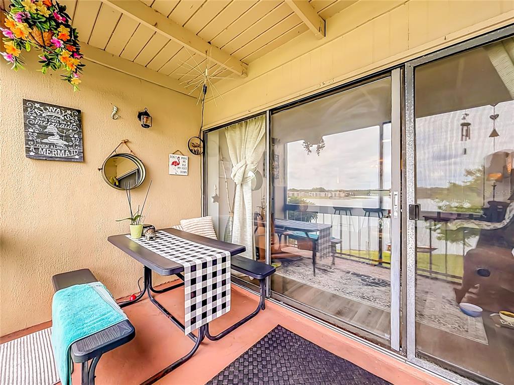 A covered patio features a picnic-style table, bench seating, and sliding glass doors overlooking water — 574 ORANGE DRIVE UNIT 78, ALTAMONTE SPRINGS, FL