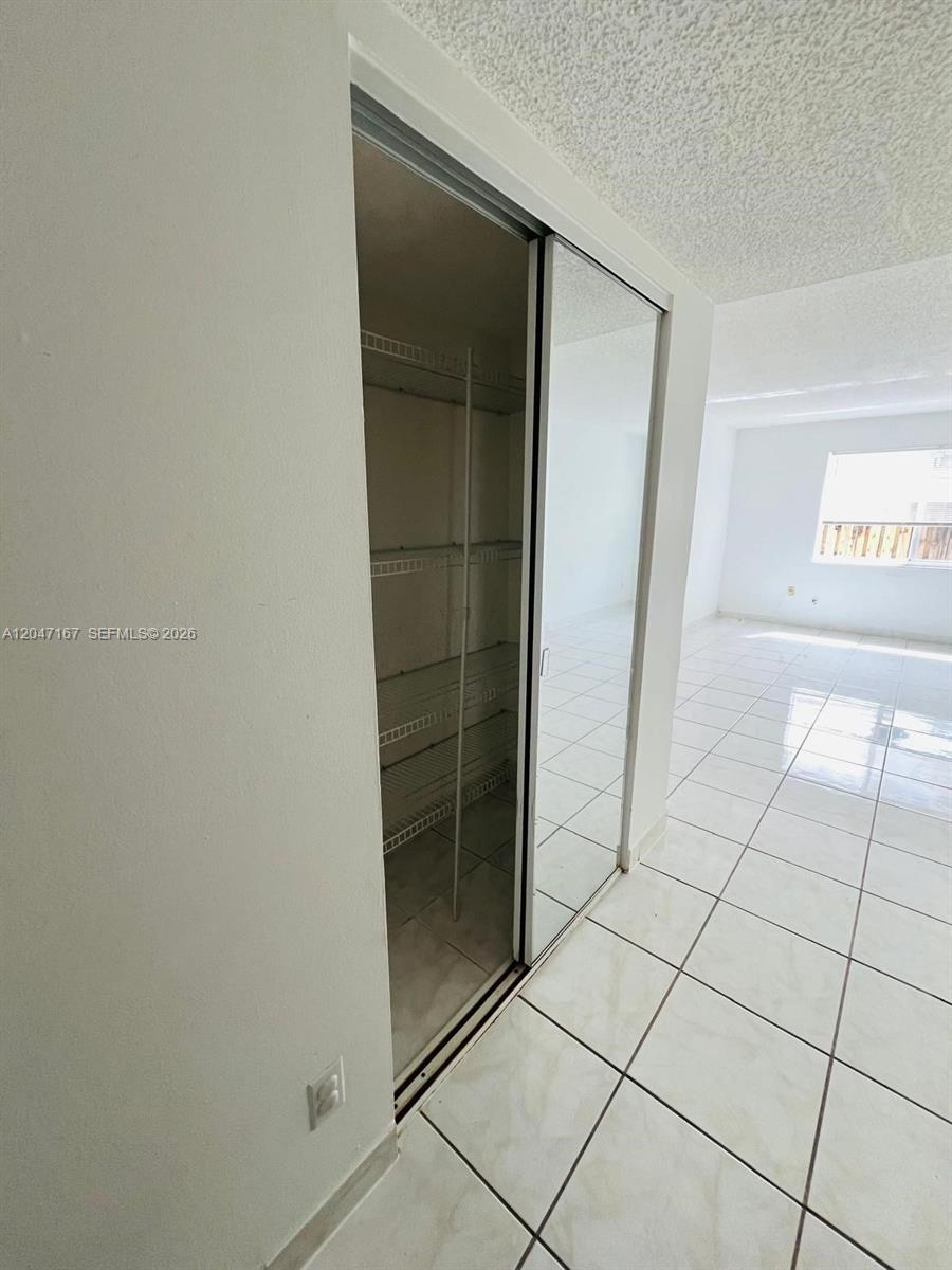 A closet with wire shelving sits next to a tiled room with a window — 724 NE 4th St # 5, Hallandale Beach FL 33009, HALLANDALE BEACH, FL