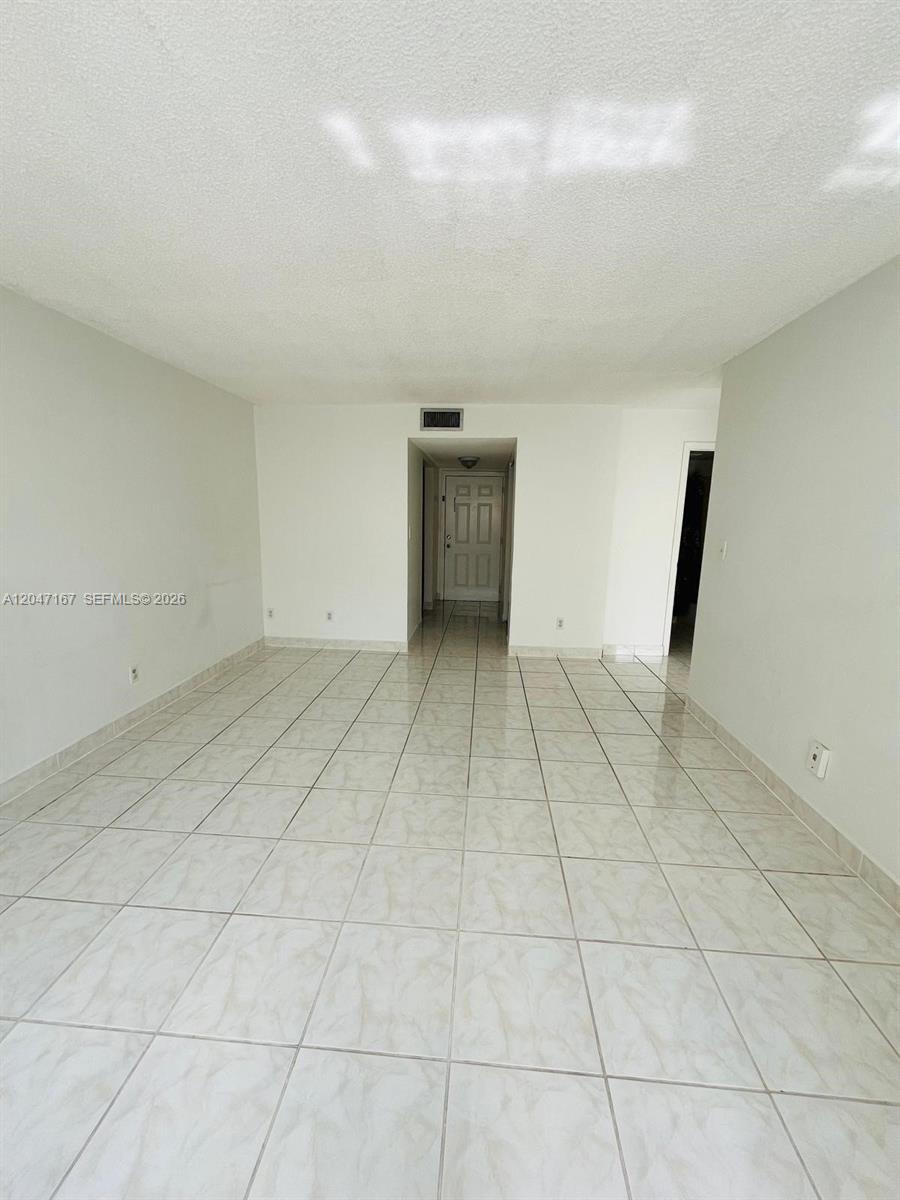 An empty room with light-colored tile flooring and a white door in the distance — 724 NE 4th St # 5, Hallandale Beach FL 33009, HALLANDALE BEACH, FL