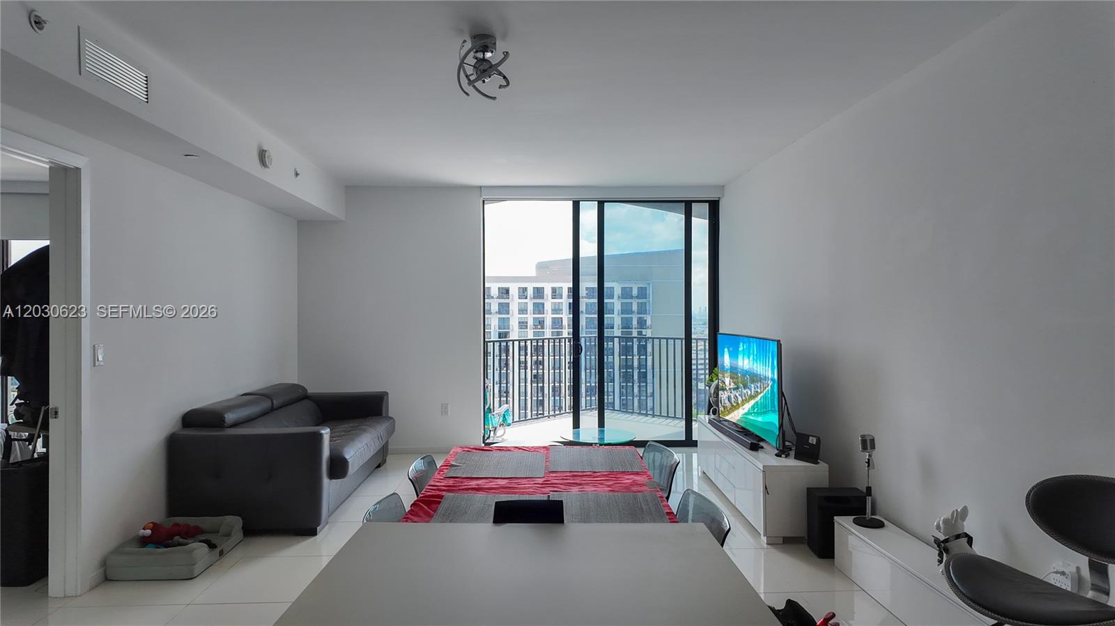 A modern living and dining area features white walls, tile floors, and a balcony view — 5300 Paseo Blvd # 1807, Doral FL 33166, DORAL, FL