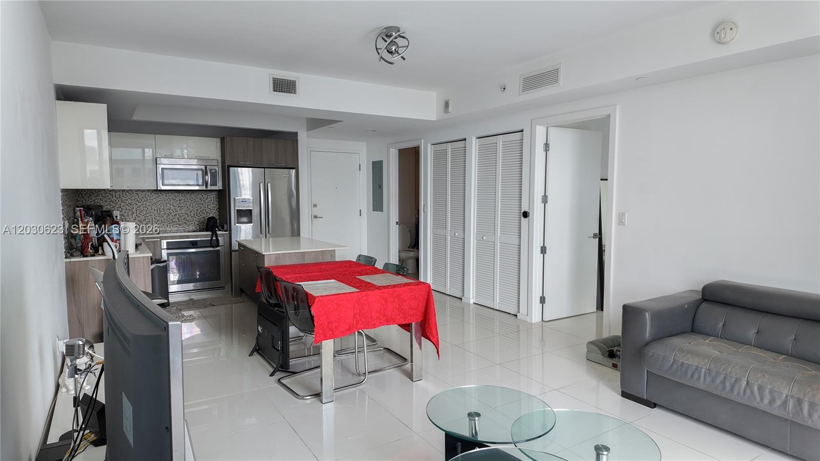 An open-concept living area features a kitchen with stainless steel appliances, a dining table, and a sofa — 5300 Paseo Blvd # 1807, Doral FL 33166, DORAL, FL