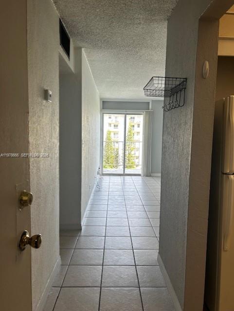 A tiled hallway leads toward a sliding glass door opening onto a balcony — 801 NW 47th Ave # 717W, Miami FL 33126, MIAMI, FL