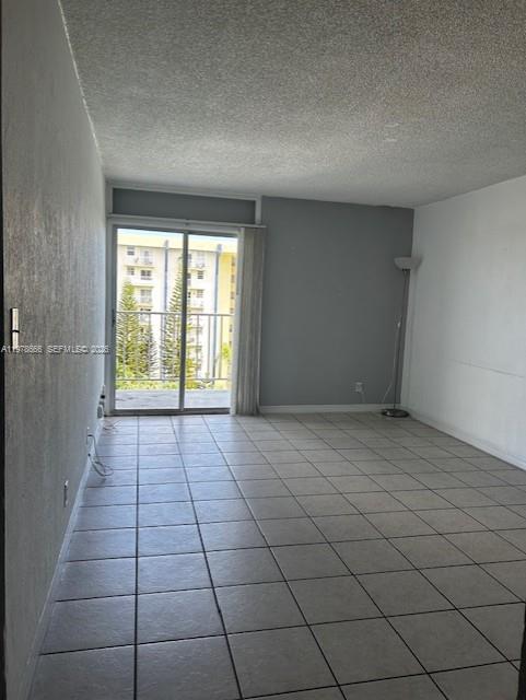 An empty room with light-colored tile flooring, a sliding glass door, and a balcony view — 801 NW 47th Ave # 717W, Miami FL 33126, MIAMI, FL
