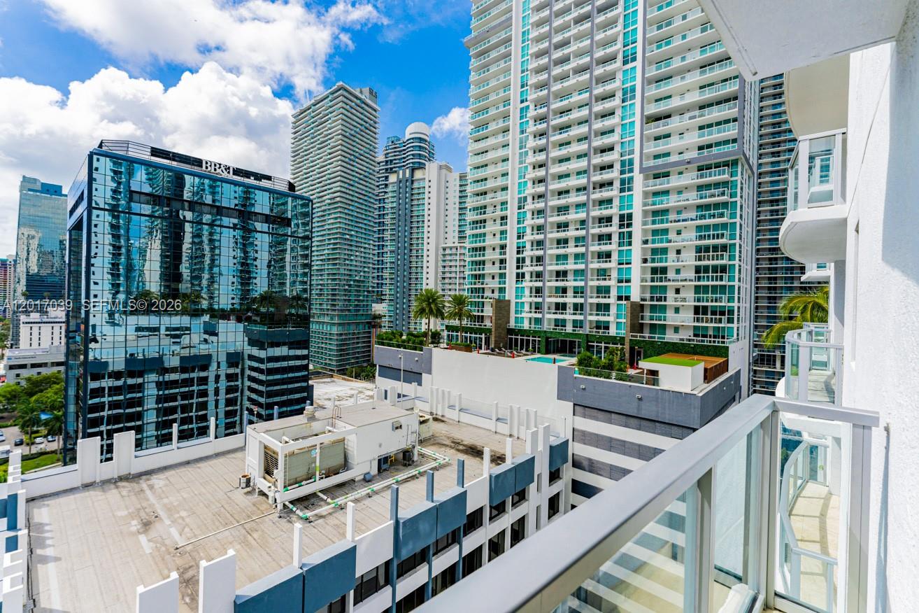 A kitchen with light wood cabinets, black countertops, and a stacked washer-dryer unit — MIAMI, FL