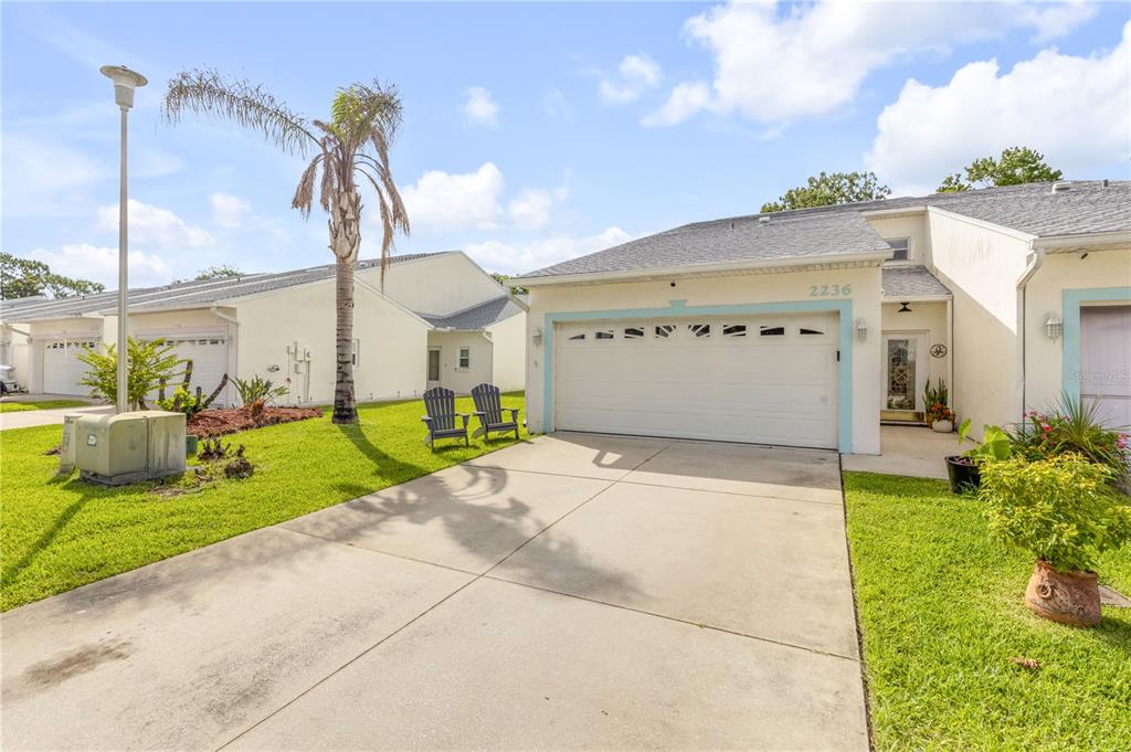A single-story residential building with a white garage, driveway, and a palm tree — 2236 DEERWOOD DRIVE, NEW SMYRNA BEACH, FL