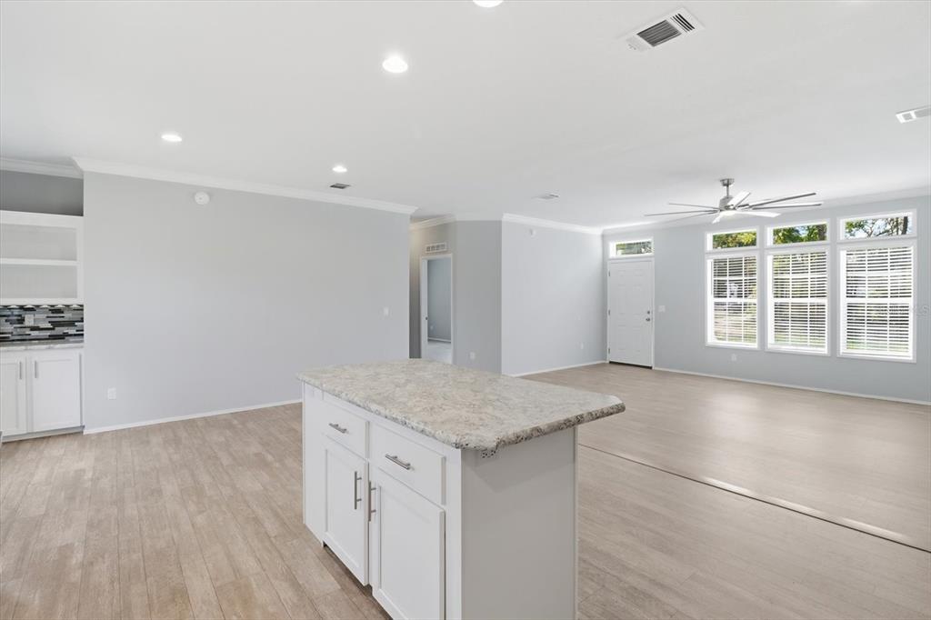 An open-concept kitchen and living area features a stone-topped island, light flooring, and recessed lighting — 6735 W HOMOSASSA TRAIL, HOMOSASSA, FL